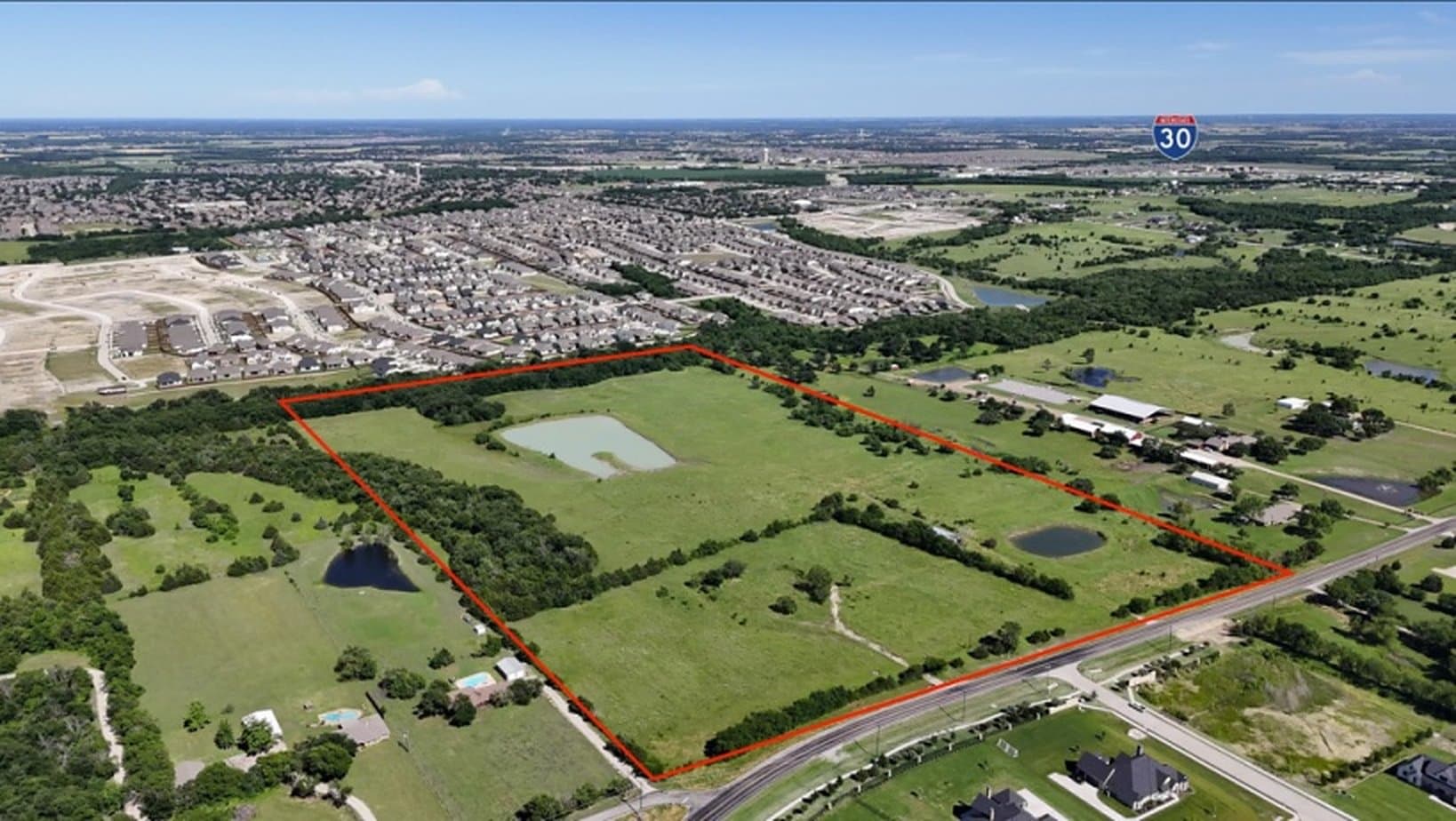Aerial view of the 54.28-acre site outlined in red along N Stodghill Road, with the Interstate 30 marker on the horizon